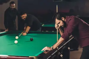 Игрок в бильярд опустил голову и выглядит расстроенным после промаха